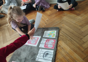 Na zdjęciu widzimy dziewczynkę, która przyporządkowuje do ułożonych puzzli ilustrację przedstawiającą godło Polski.