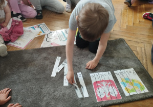 Na zdjęciu widzimy chłopca, który układa puzzle - złotówka.