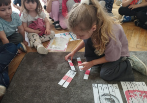 Na zdjęciu widzimy dziewczynkę, która układa puzzle - flaga Polski.