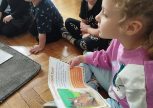 Na zdjęciu widzimy dziewczynkę, która trzyma ilustrację przedstawiającą informacje o Międzynarodowym Dniu Konia.