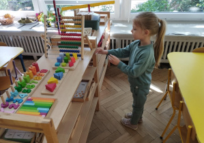 Na zdjęciu widzimy dziewczynkę, która odnalazła kartkę z ilustracją motyla, która znajdowała się na szafce z materiałem z działu matematycznego.