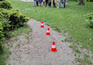 dzieci w ogrodzie stoją przed slalomem