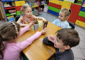 Zdjęcie przedstawia dzieci siedzące przy stoliku.
