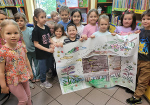 Zdjęcie przedstawia dzieci pozujące do zdjęcia, trzymając prace plastyczną.