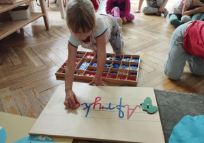 Na zdjęciu widzimy dziewczynkę, która z wykorzystaniem ruchomego alfabetu pisze nazwę "Afryka".