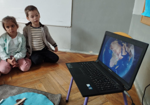Na zdjęciu widzimy dwójkę dzieci, które oglądają film edukacyjny o Afryce.