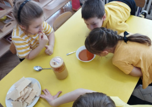 Na zdjęciu widzimy dziewczynkę, która wącha miód w miseczce.