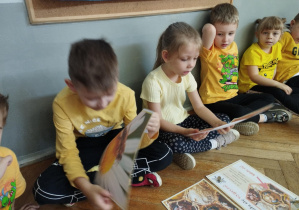 Na zdjęciu widzimy dzieci, które oglądają zdjęcia z pszczołami.