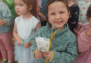 Na zdjęciu chłopiec, który trzyma nagrodę pieniężną