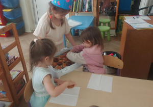 Dziewczynka częstuje inne dzieci przygotowaną niespodzianką