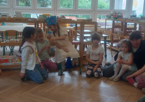 Na zdjęciu grupa dzieci, która ogląda zdjęcia przyniesione przez dziewczynkę