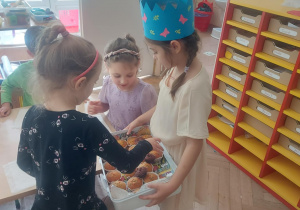Na zdjęciu dziewczynka, jubilatka, która rozdaje słodką niespodziankę