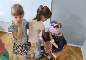 Na zdjęciu widzimy dziewczynkę, która częstuje się cukierkiem.