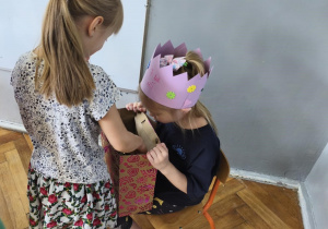 Na zdjęciu widzimy dziewczynkę, która częstuje się cukierkiem.