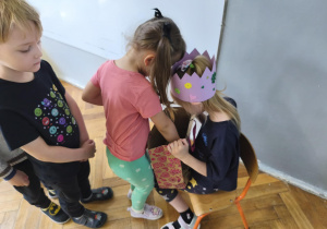 Na zdjęciu widzimy dziewczynkę, która częstuje się cukierkiem.