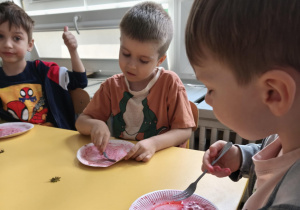 Dzieci gniotą truskawki widelcem