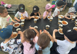 Zdjęcie przedstawia dzieci siedzące spagetti.