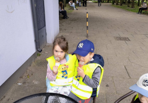Zdjęcie przedstawia dwójkę dzieci siedzących na wspólnym krześle, jedzących lody.