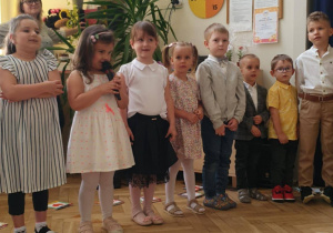 Zdjęcie przedstawia dziewczynkę mówiącą do mikrofonu.