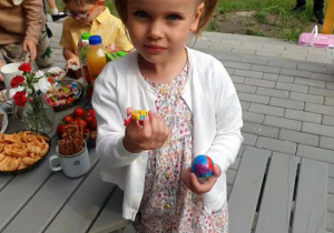 Zdjęcie przedstawia dziewczynkę z cukierkiem w ręku.