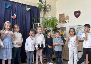 Zdjęcie przedstawia dzieci stojące w rzędzie.