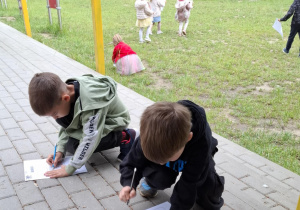 dzieci zakreślają obrazki na kartkach