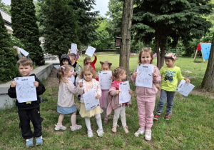 dzieci stoją w ogrodzie, w rękach trzymają kartki z napisem bingo