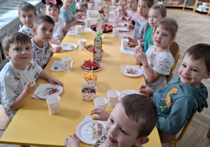 dzieci siedzą przy stole urodzinowym