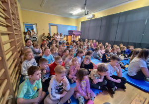 Na zdjęciu widzimy grupkę dzieci oczekującą na przedstawienie.
