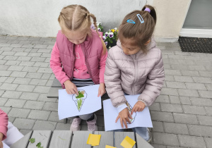 Na zdjęciu widzimy dziewczynki, które przyklejają materiał naturalny na szablony.