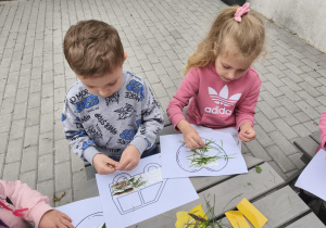 Na zdjęciu widzimy dzieci, które przyklejają materiał naturalny na szablony.