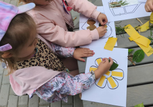 Na zdjęciu widzimy dzieci, które przyklejają materiał naturalny na szablony.