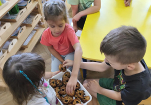 Na zdjęciu widzimy dziewczynkę, która rozdaje dzieciom zdrowe ciasteczka.