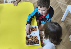 Na zdjęciu widzimy dziewczynkę, która rozdaje dzieciom zdrowe ciasteczka.