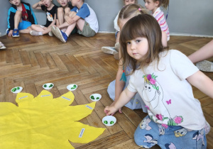 Na zdjęciu widzimy dziewczynkę, która rozkłada koraliki do miseczek. Koraliki oznaczają kolejne lata życia dziewczynki.