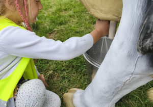 Na zdjęciu widzimy dzieci, które doją krowę edukacyjną.