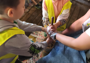 Na zdjęciu widzimy dzieci, które pomagają pani gospodyni Zagrody w tworzeniu masła.