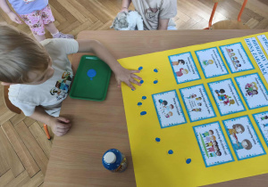 Na zdjęciu widzimy chłopca, który odciska umoczony w farbie palec na plakacie z zasadami.