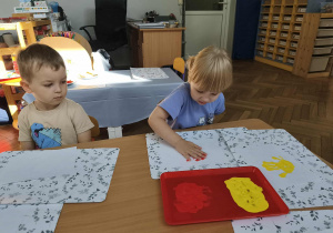 Na zdjęciu widzimy dziewczynkę, która odciska dłoń na kartce.