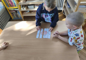 Na zdjęciu widzimy dziewczynkę, która układa puzzle z ilustracją wesołej kropki.