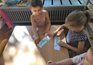 Na zdjęciu dwie dziewczynki, które wspólnie starają się ułożyć puzzle z kropką.