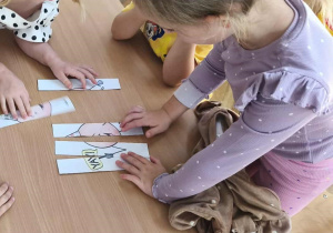 Na zdjęciu dwie dziewczynki, które wspólnie starają się ułożyć puzzle z kropką.
