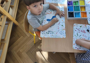 Na zdjęciu widzimy chłopca, który tworzy pracę plastyczną z wykorzystaniem kropek z plasteliny.