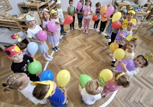 dzieci stoją na elipsie, w dłoniach trzymają balony