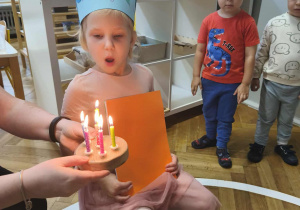 Na zdjęciu widzimy dziewczynkę dmuchającą świeczki.