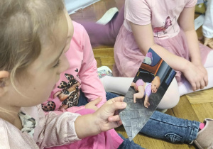 Na zdjęciu widzimy dwie dziewczynki, które oglądają zdjęcia z poszczególnych etapów życia Solenizantki.