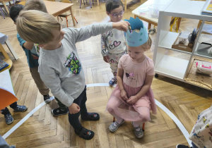 Na zdjęciu widzimy chłopca, który wkłada na głowę Solenizantki koronę.