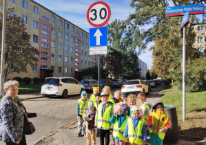 Dzieci stoją na ulicy i obserwują znaki drgowe.