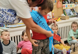 nauczyciel zakładający szarfę z imieniem chłopcu