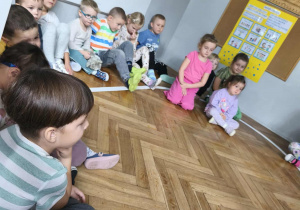 Na zdjęciu widzimy grupkę dzieci, które słuchają czytanej bajki.